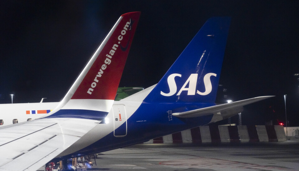 Detaljfoto av to fly ved siden av hverandre på Bergen Lufthavn Flesland. Det ene med SAS-logo på halen, det andre med Norwegian-logo på vingen.