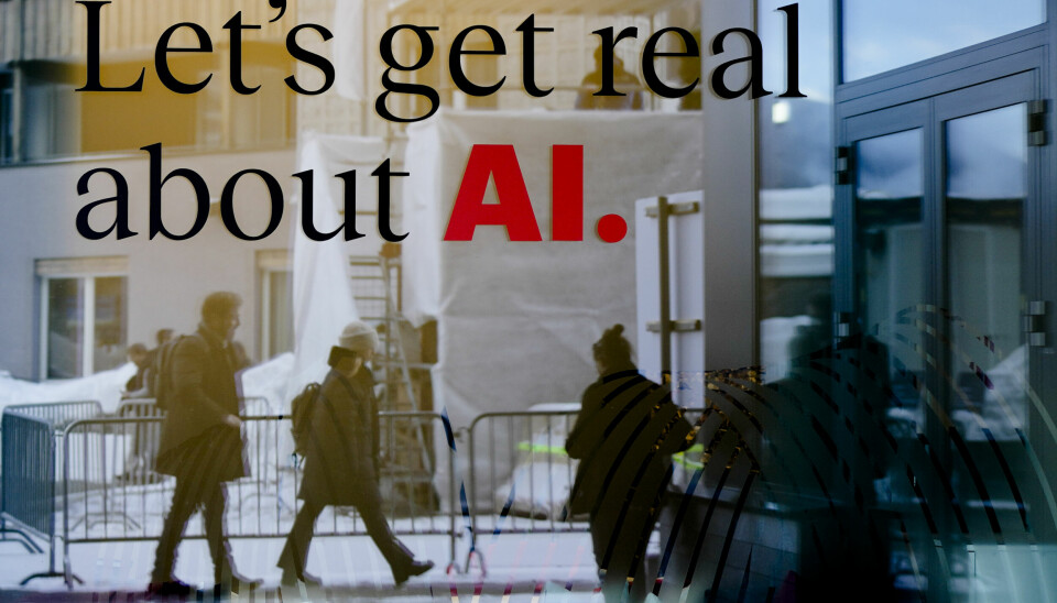 Bilde av et skilt på et utstillingsvindu: Let's get real about AI. Mennesker går i bakgrunnen.