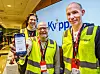 Gruppebilde med de tre, som holder fram en telefon som viser Kvipp-løsningen. De har på seg gule vester, og Kvipp-logoen vises på en skjerm bak dem.
