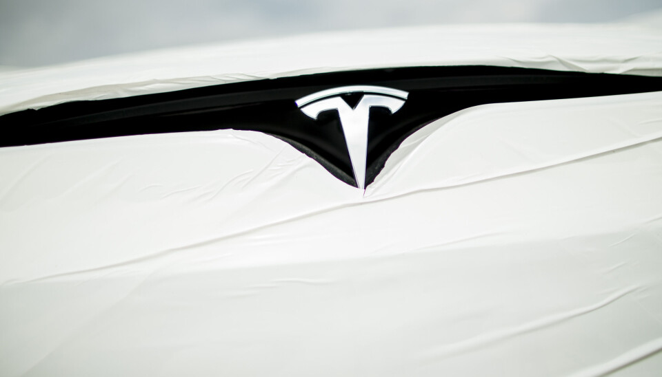 TAPTE: Tesla må ut med 150.000 kroner til en varsler. Nærbilde av Tesla-logoen på en ny bil pakket inn i plastfolie.