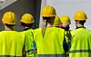 Gruppe med industriarbeidere i refleksvester og gule hjelmer.