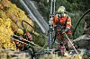 To arbeidere arbeider med fjellsikring, høyt oppe i en fjellside. De bruker verne- og fallsikringsutstyr.