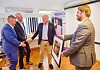 Fire menn snakker sammen i et kontorrom med bilder, stativ og et MDCO-skilt i bakgrunnen.
