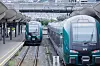 To Vy-tog står på parallelle spor ved Oslo sentralstasjon under stasjonens glasstak.