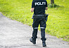 Politibetjent sett bakfra på en asfaltert gangvei mellom grønne gressflater.