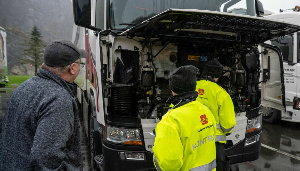 Kontrollører fra Statens vegvesen studerer motorrommet på en lastebil.