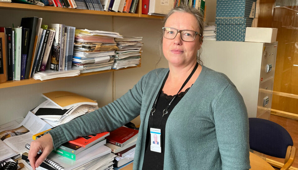 Brita Bjørkelo fotografert på et kontor med masse bøker og papirer.