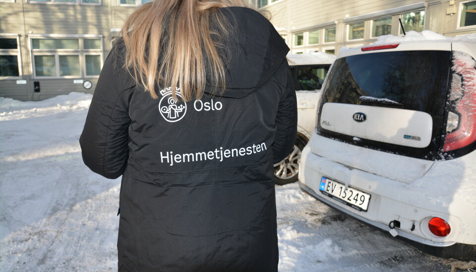 Kvinne med ryggen til iført parkasen. Ryggen er dekorert med Oslos byvåpen og «Hjemmetjenesten»