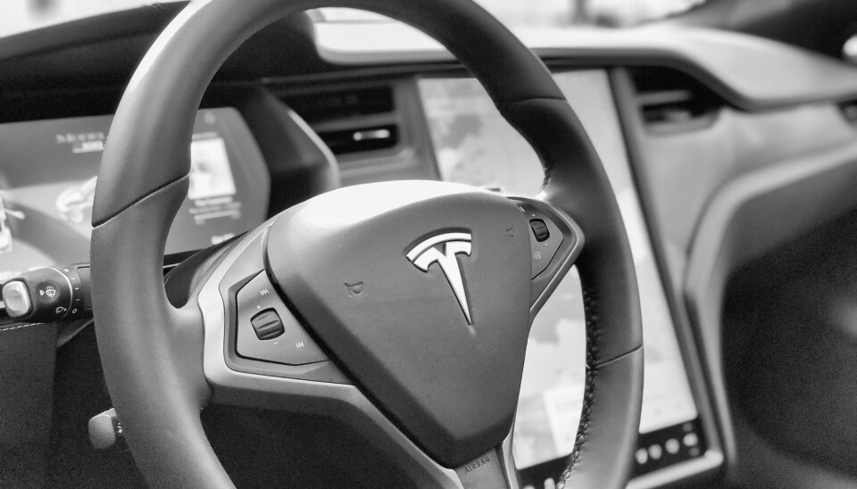 Nærbilde av rattet i en Tesla, med Tesla-logoen i midten.
