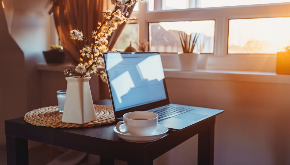 VIL VÆRE HER: Hver tredje arbeidstaker ønsker mer hjemmekontor, ofte for å slippe pendling. Bilde av PC på et bord med kaffekopp, i hjemmemiljø.