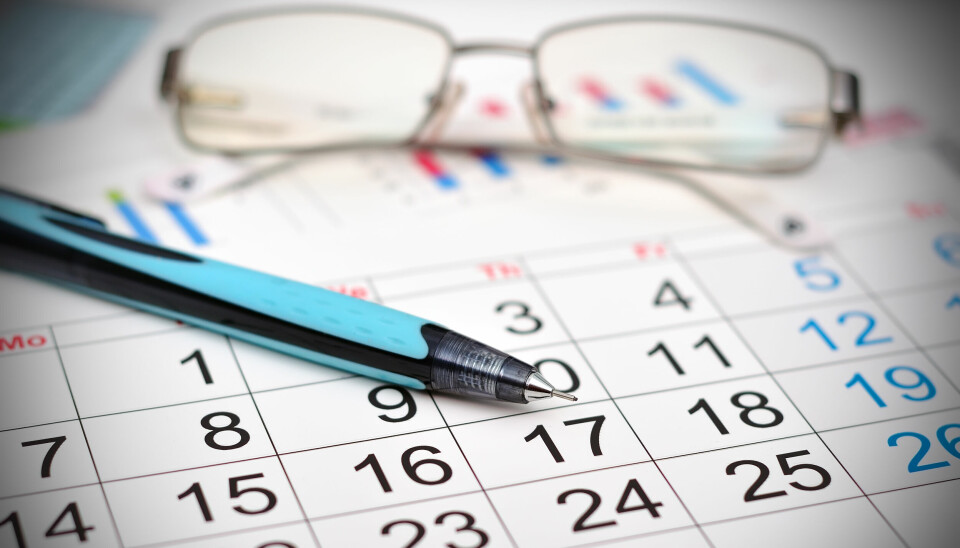 Et par briller og en penn dandert oppå en bordkalender.