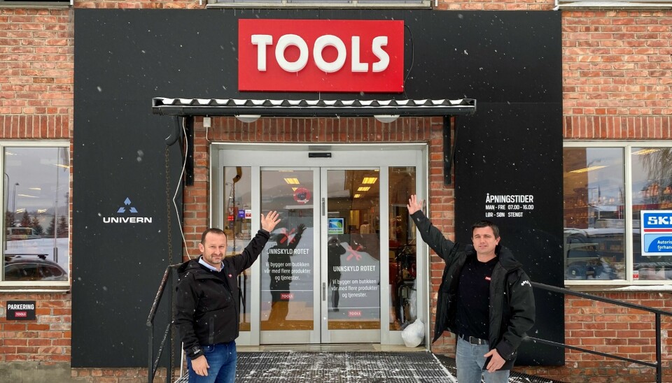 De to poserer utenfor inngangsdøren til butikken der det er et Tools-skilt over døren.