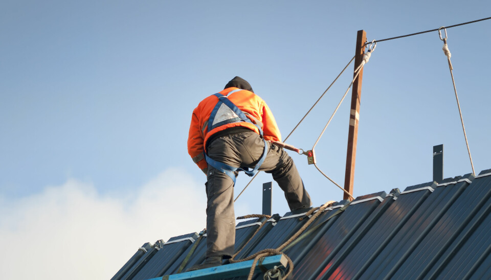 Bygningsarbeider arbeider med sikring på et tak.