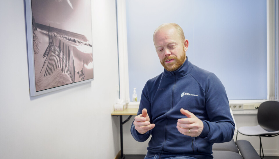 FOLKEHELSE: Det finnes ingen kvikk fiks mot vonde skuldre, nakker og rygger. Plagene må ses i lys av den enkelte pasientenes livssituasjon, forklarer Tomas Collin. Her er han fotografert på i et behandlingsrom på Høgskolen Kristiania, der den norske osteopatutdanningen holder til. Tomas Collin sitter på en behandlingsbenk og snakker. Han ser på hendene sine.