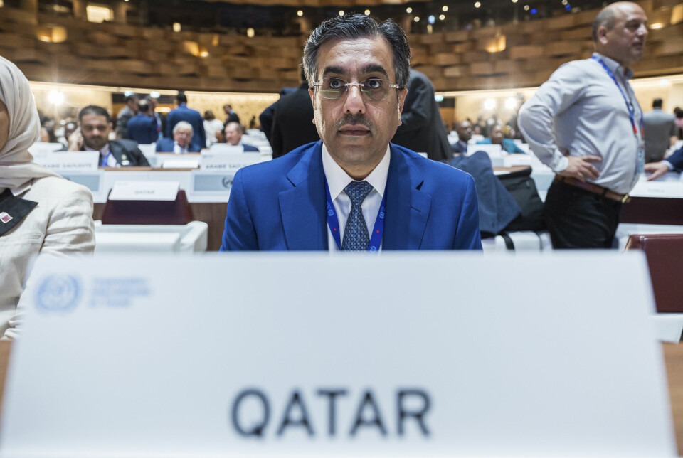 Ministeren i en konferansesal med et skilt foran seg der det står Qatar.