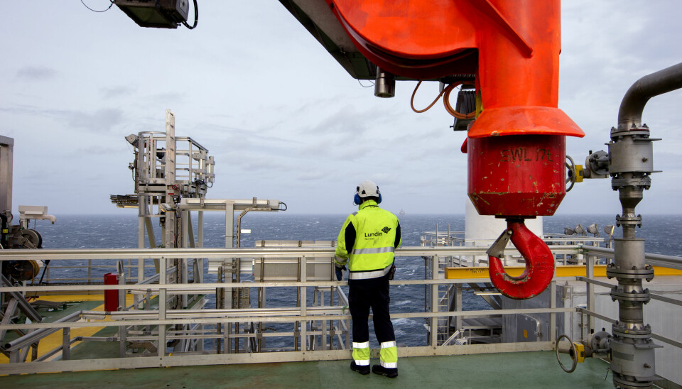 Oljearbeider på plattform med ryggen til, står og ser ut over sjøen.