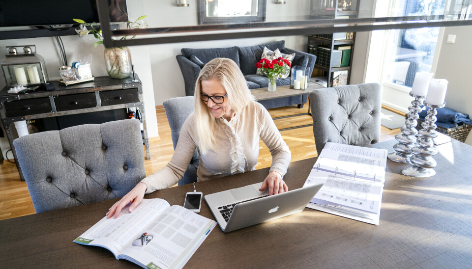 HYBRID: Vel én av tre arbeidstakere, 36 prosent, sier de jobber hele dager på hjemmekontor. Kvinne sitter ved spisebordet i en stue og arbeider med PC.