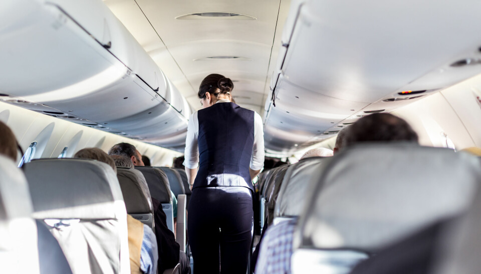 Kvinnelig kabinansatt i midtgangen på fly.